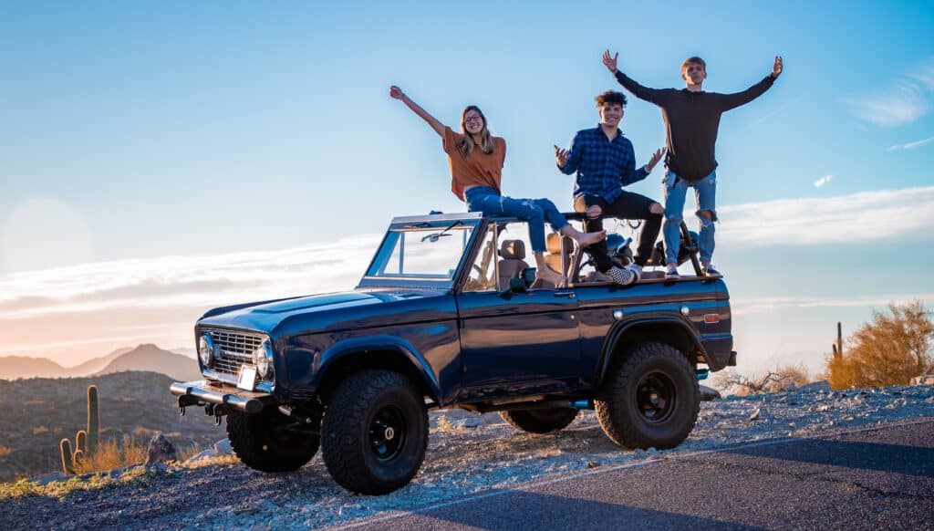 Car with people on top taking a photo